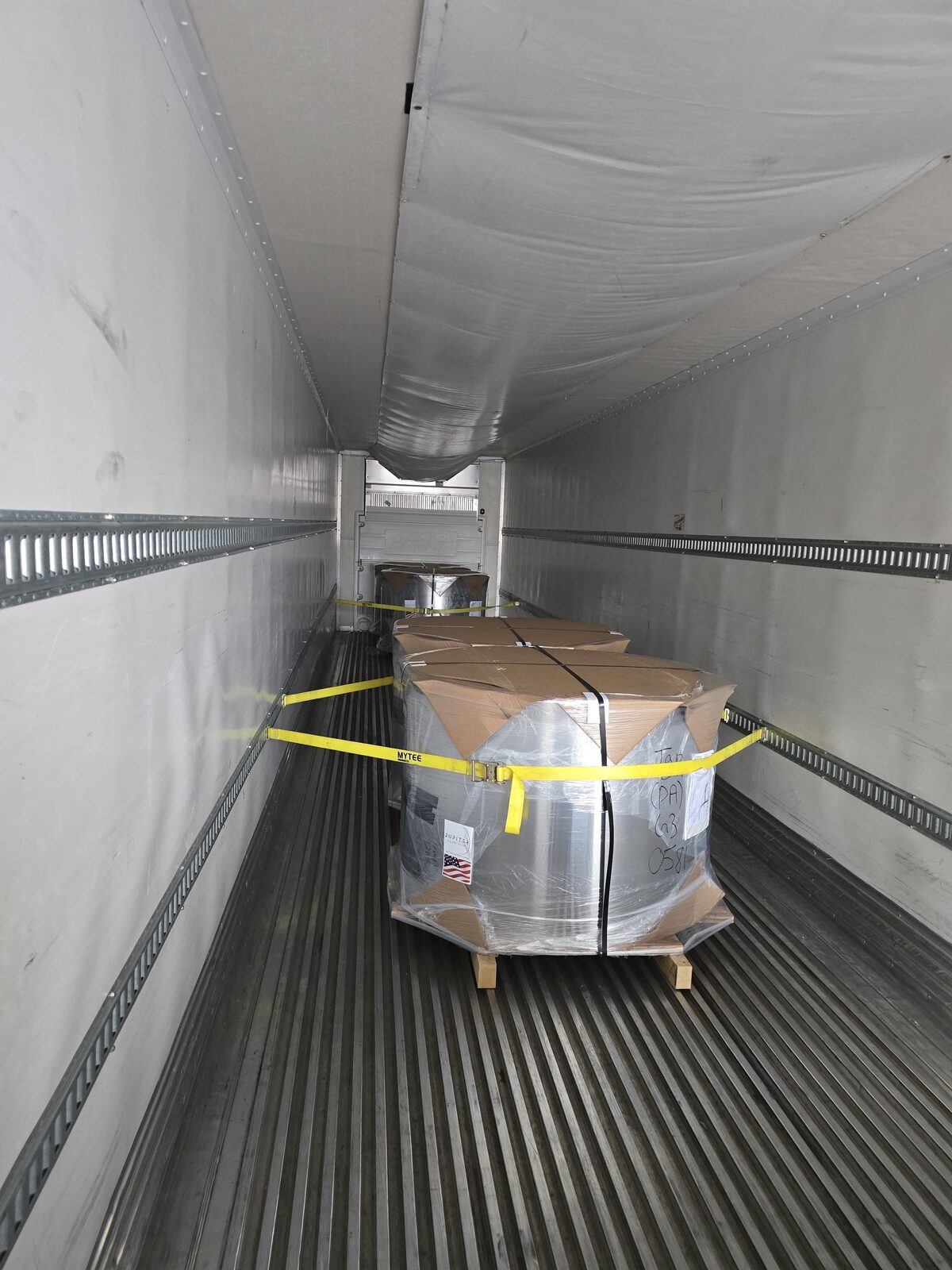 Wrapped metal coils secured on pallets inside a DT Trans LLC reefer trailer